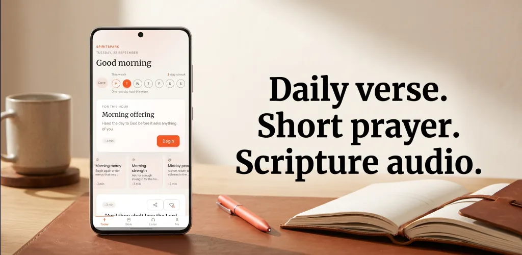 SpiritSpark on a desk beside an open journal. The phone says Good morning and Morning offering. Beside it: Daily verse. Short prayer. Scripture audio.